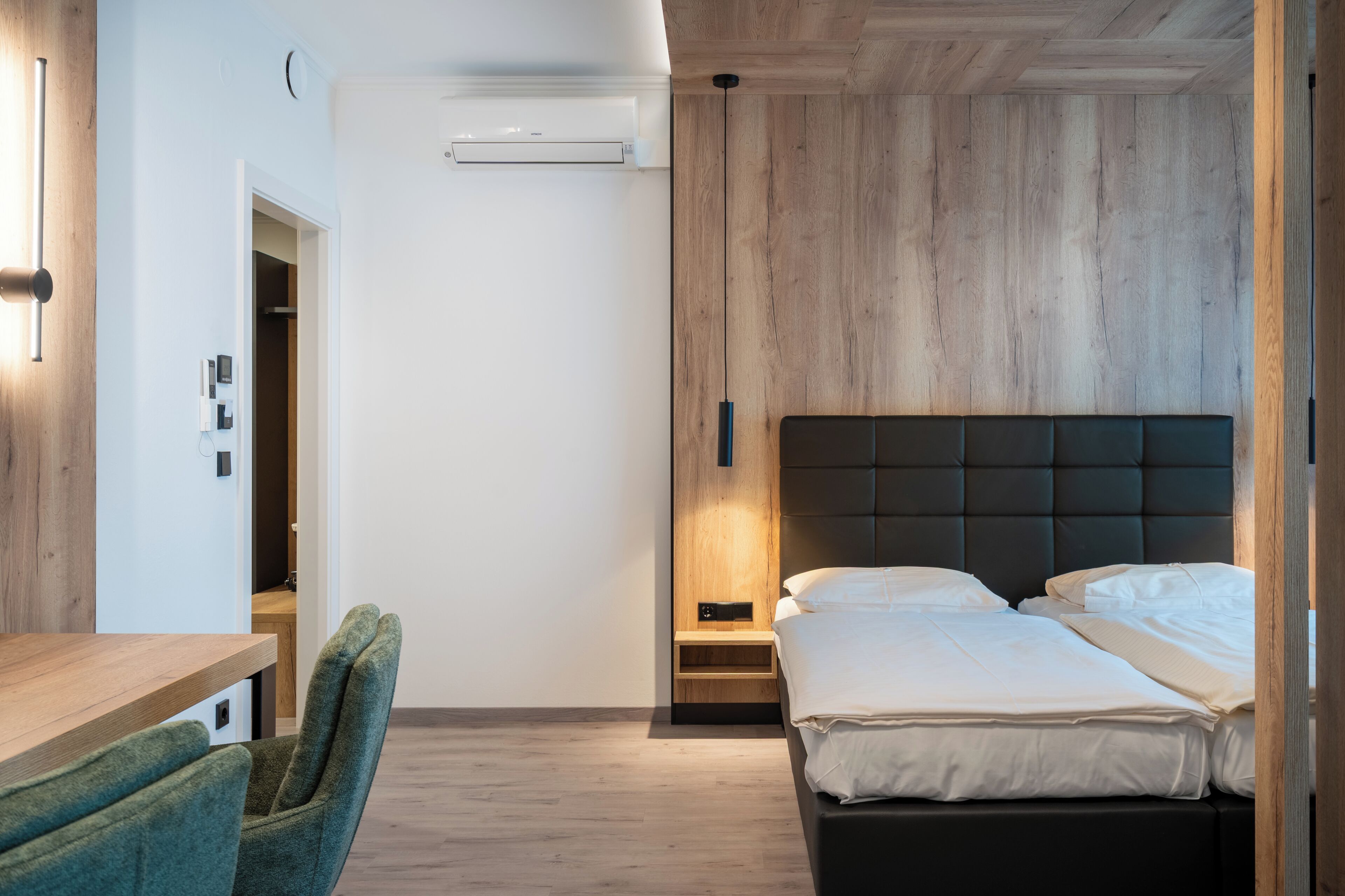 A modern bedroom with a wooden headboard, a bedside table, and a chair.