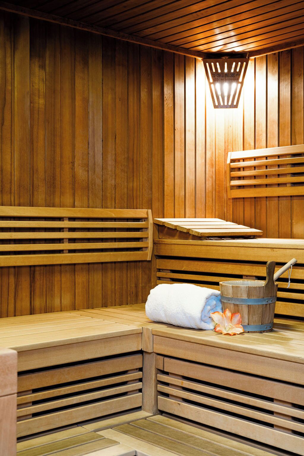 Un sauna avec des bancs en bois, une serviette et un seau.