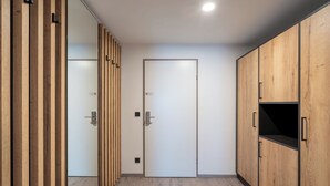 A hallway with wooden paneling, a white door, and a black cabinet.