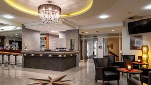 A hotel lobby with a reception desk, seating area, and a large star-shaped floor design.