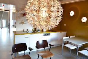 Une cuisine moderne dotée d’un îlot central, de meubles blancs et d’un luminaire décoratif.
