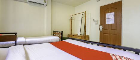 A hotel room with two beds, a wooden dresser, a mirror, and a door with a notice.