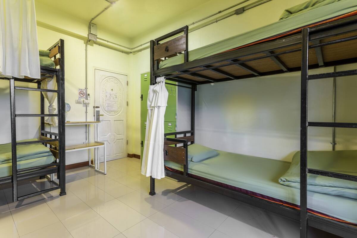 A dormitory room with bunk beds, a white door, and a green cabinet.