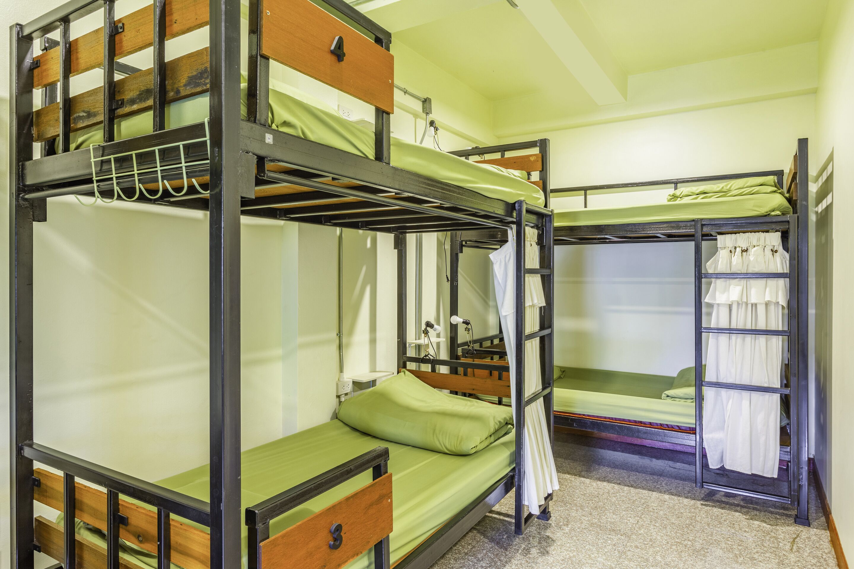 A bunk bed room with a wooden ladder, a desk, and a chair.