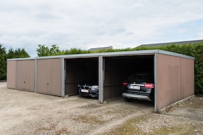 A metal building with two open garage doors, each housing a car.
