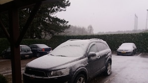 A parking area with several cars covered in snow, indicating a snowy weather condition. - Hotel Apollo (Zutendaal)