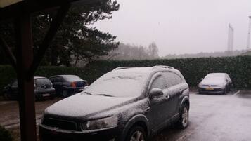 Een parkeerplaats met diverse auto's bedekt met sneeuw, wat duidt op winterse omstandigheden.