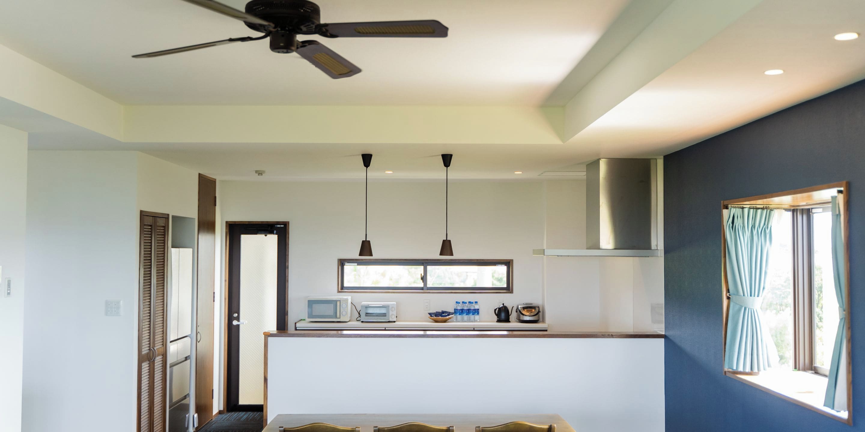 Una cocina moderna con comedor, ventilador de techo y ventana con cortinas.