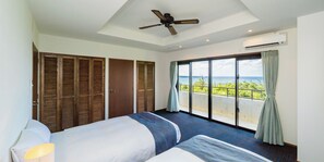 Une chambre d’hôtel avec un lit, un ventilateur de plafond, un appareil de climatisation et un balcon avec vue.