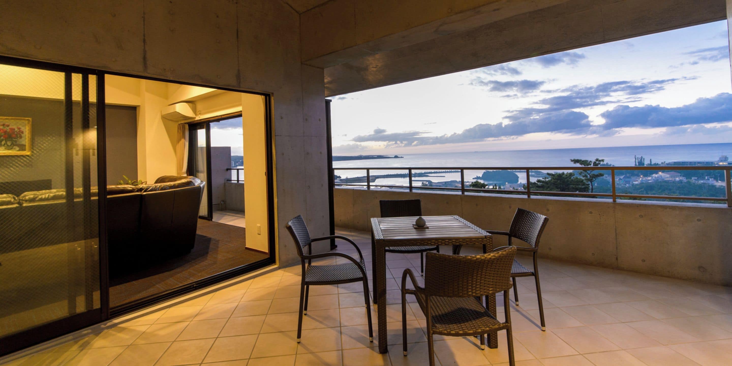Varanda com mesa e cadeiras, vista para o mar e um vislumbre do interior.