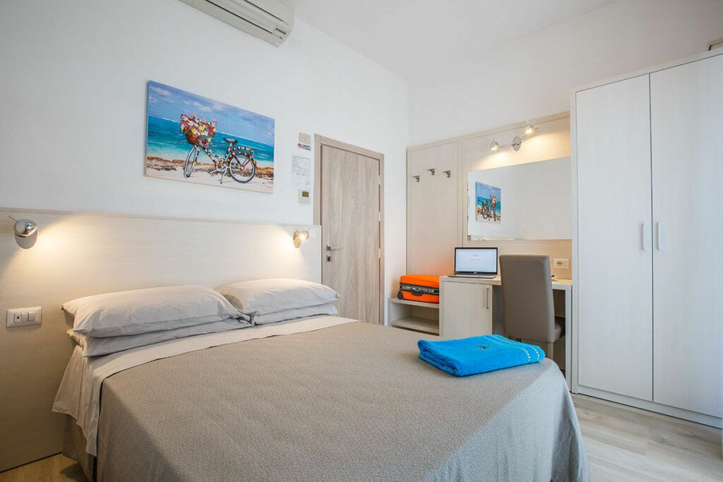 Une chambre à coucher avec un lit, un bureau avec un ordinateur portable et une armoire.