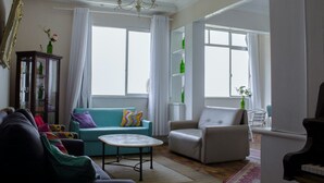 A living room with a sofa, armchairs, a coffee table, a piano, and a cabinet with bottles. - Aconchego Frente Mar (Rio de Janeiro)