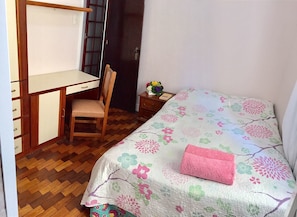 Quarto com uma cama, uma escrivaninha e uma cadeira.
