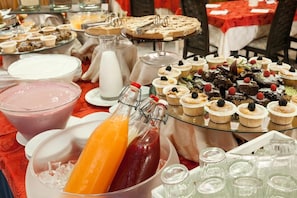 A buffet table with various food items, including desserts and beverages.