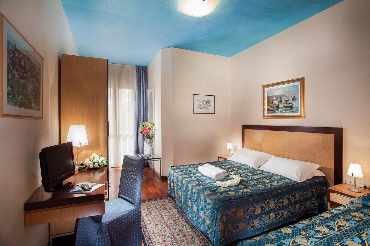 Une chambre d’h ôtel avec un lit, un bureau avec un ordinateur, une chaise et un téléviseur.