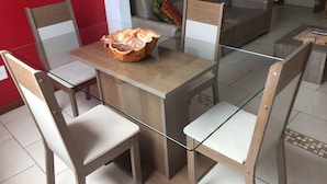 Een eetgedeelte met een tafel met glazen blad, vier stoelen en een decoratieve schaal op de tafel.