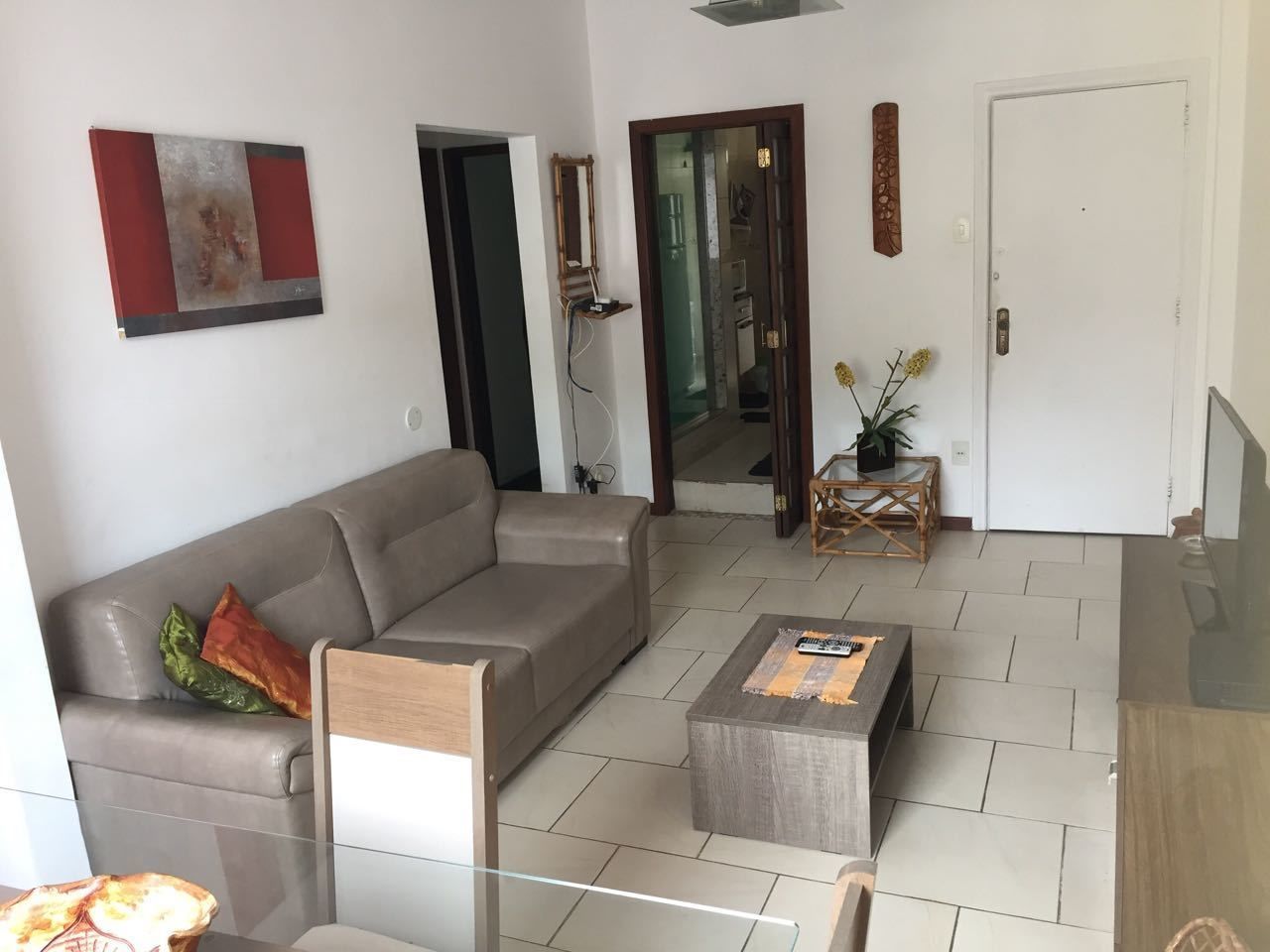 Een moderne woonkamer met een grijze bank, een houten salontafel en een glazen eettafel.