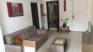 Een moderne woonkamer met een grijze bank, een houten salontafel en een glazen eettafel.
