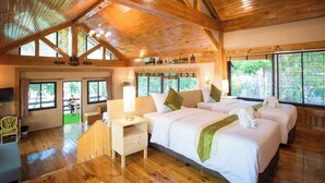 A wooden-floored room with three beds, a desk, and a chair. - Bhumisiri Hill Khaoyai (Pak Chong)