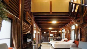 A cozy cabin-style room with wooden walls, a large bed, a desk, and a television. - Bhumisiri Hill Khaoyai (Pak Chong)