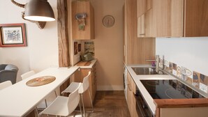 Une cuisine compacte avec des meubles en bois, un plan de travail blanc et une cuisinière intégrée.