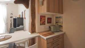 Une cuisine avec des meubles de rangement en bois, un plan de travail blanc, une horloge et divers éléments de décoration murale.