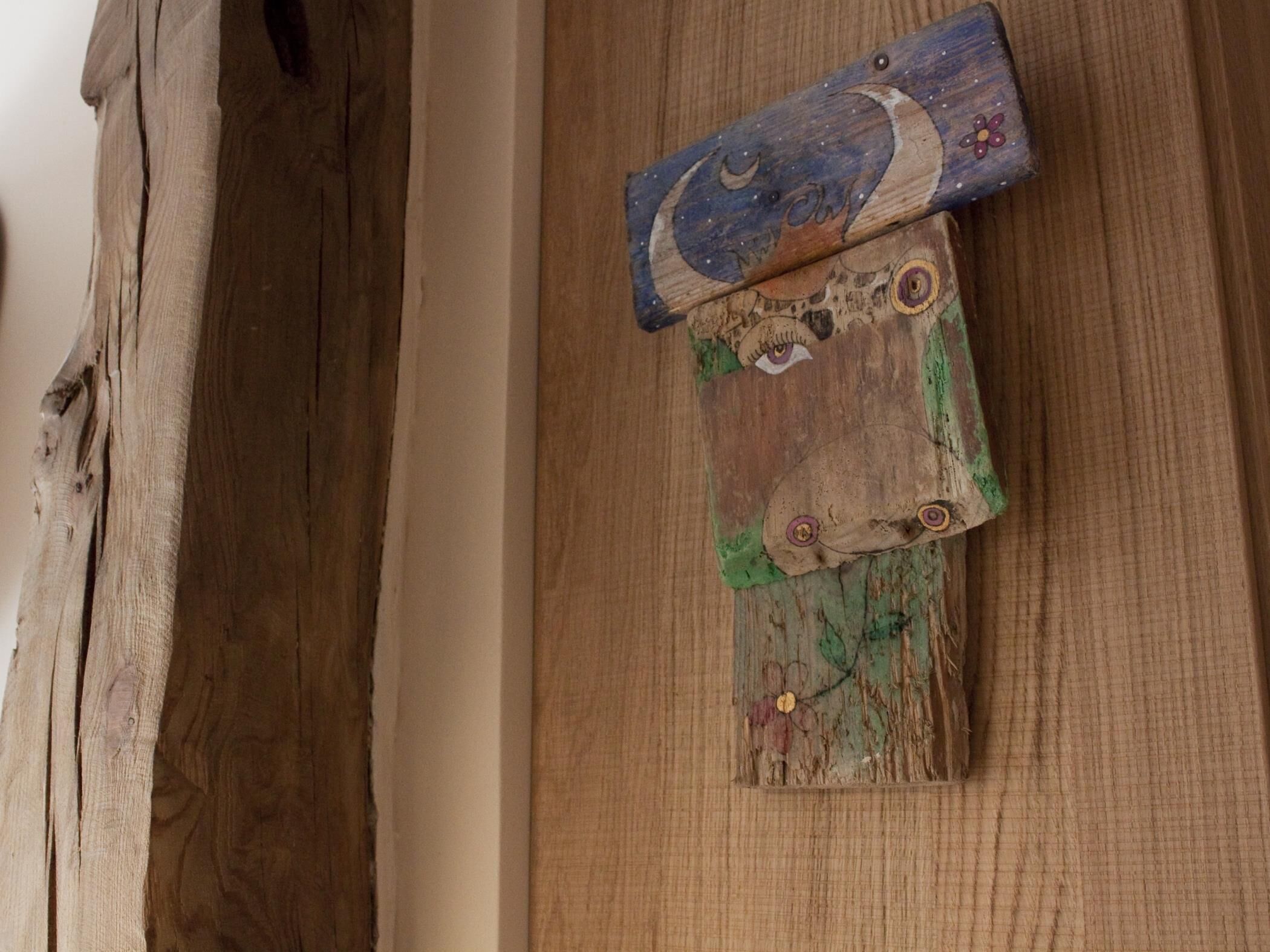A wooden wall with three distinct panels, each featuring unique carvings and designs.