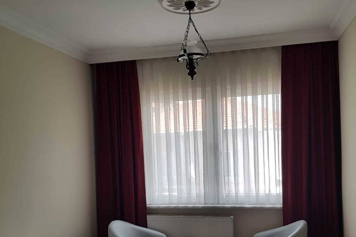 A hotel room with a bed, two chairs, a small table, and a ceiling light fixture.