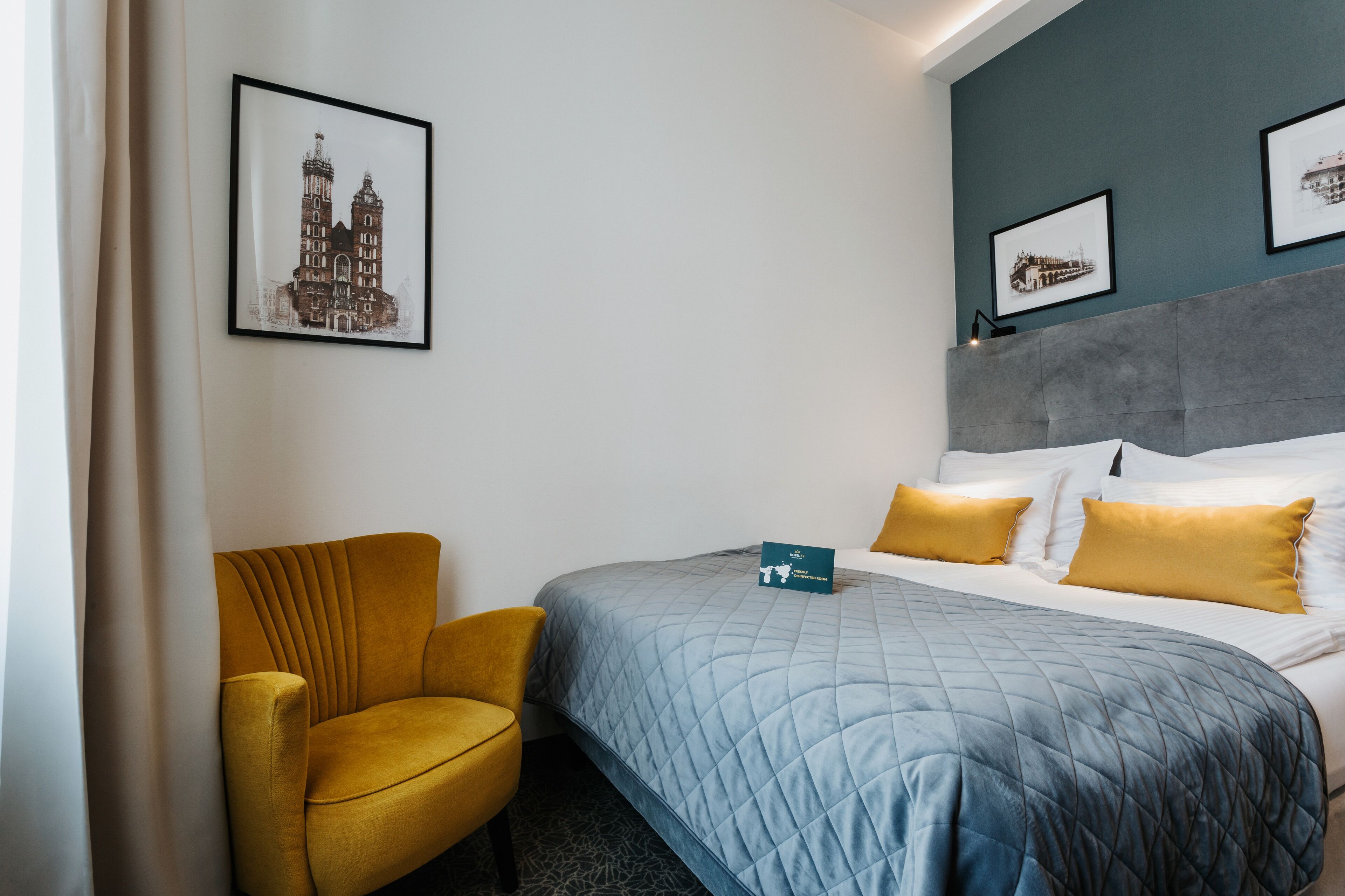 Une chambre d’hôtel avec un lit, une chaise et deux tableaux encadrés au mur.