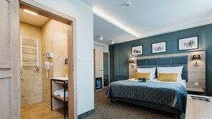 A hotel room with a bed, bedside table, and a bathroom with a towel rack and toilet.