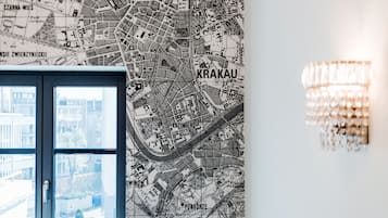 Un mapa detallado en blanco y negro de Cracovia sobre una pared, una lámpara moderna de araña y una ventana con vistas a edificios.