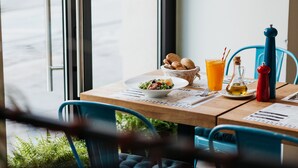 A table with a bowl of salad, a glass of orange juice, and a bottle of olive oil.