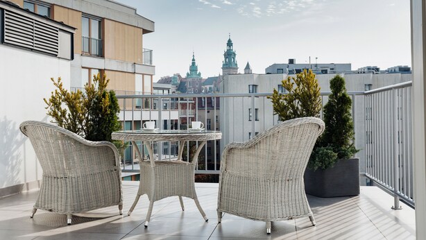 A balcony with wicker furniture, a small table, and potted plants.