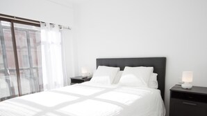 Een moderne slaapkamer met een groot bed, twee nachtkastjes en een raam met gordijnen.