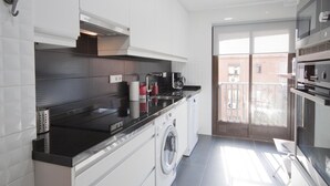 Een moderne keuken met een wasmachine, een koffieapparaat en een inbouwoven.