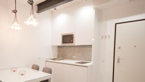 Cocina compacta equipada con microondas, lavamanos y una zona de comedor con mesa y sillas.