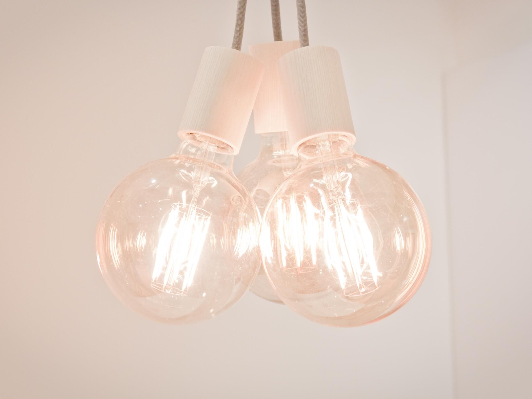 Two spherical pendant lights with a clear glass bulb and a white base, hanging from a cord.