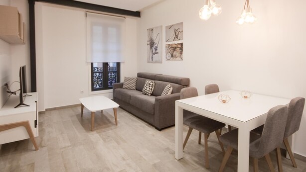 Una sala de estar moderna con un sofá, una mesa de comedor y un televisor.