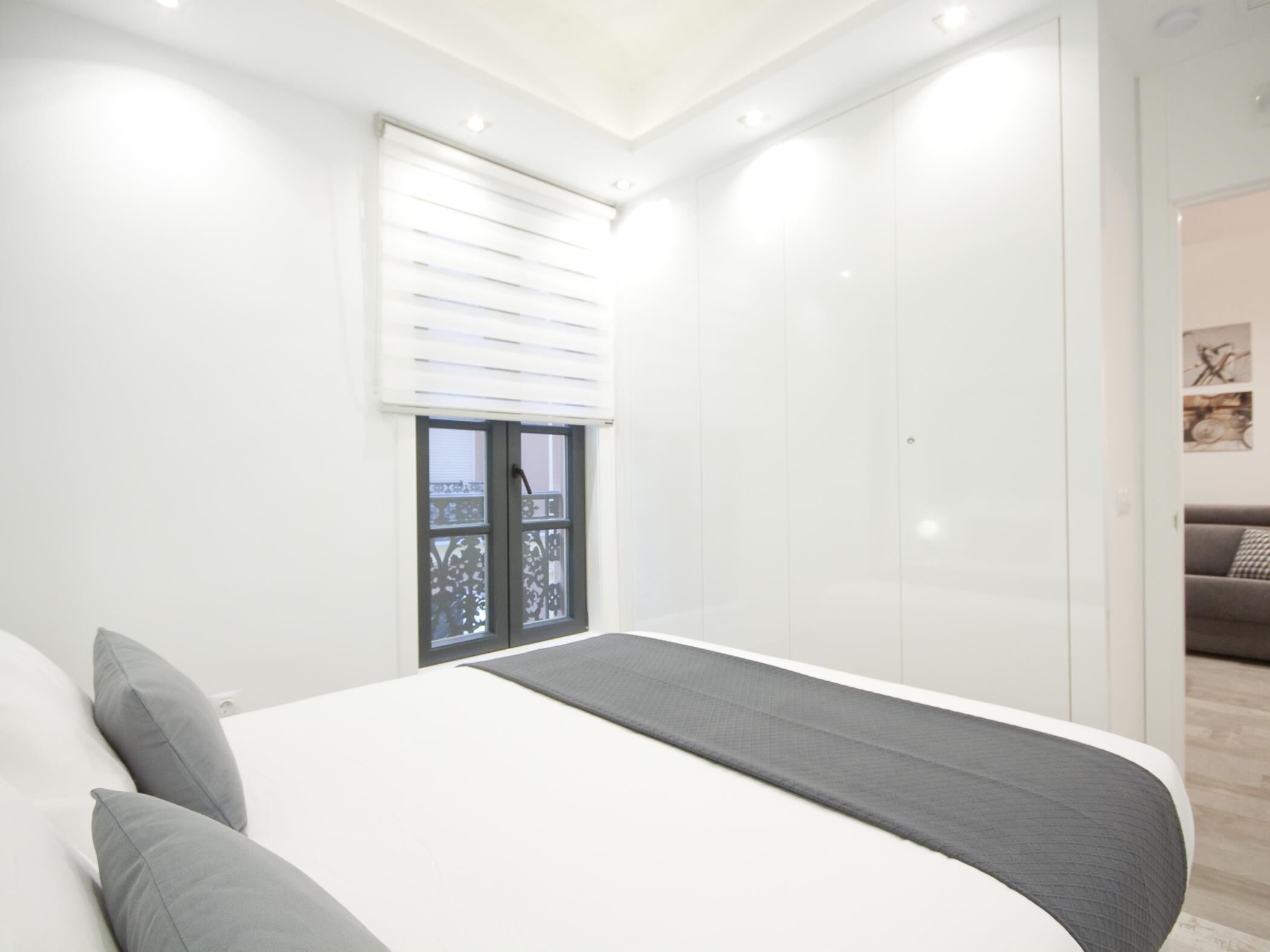 Een moderne slaapkamer met een groot bed, een raam met zonwering en uitzicht op een buitenbalkon.