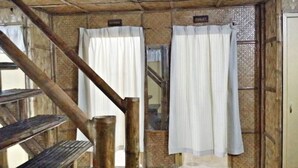 A rustic interior with wooden beams, a staircase, and a sign indicating a toilet. - V House (San Pablo)