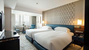 A hotel room with two beds, a desk, a chair, a TV, and a view of the city. - Lakeside Hotel Xiamen Airline (Xiamen)