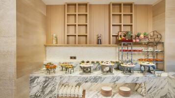 A buffet setup with various food items and a fruit display.