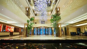A hotel lobby with a central revolving door, a reception desk, and a koi pond. - Lakeside Hotel Xiamen Airline (Xiamen)