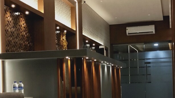 Uma área de recepção moderna com um balcão elegante, um espaço de espera com uma cadeira e um chão revestido de azulejos.
