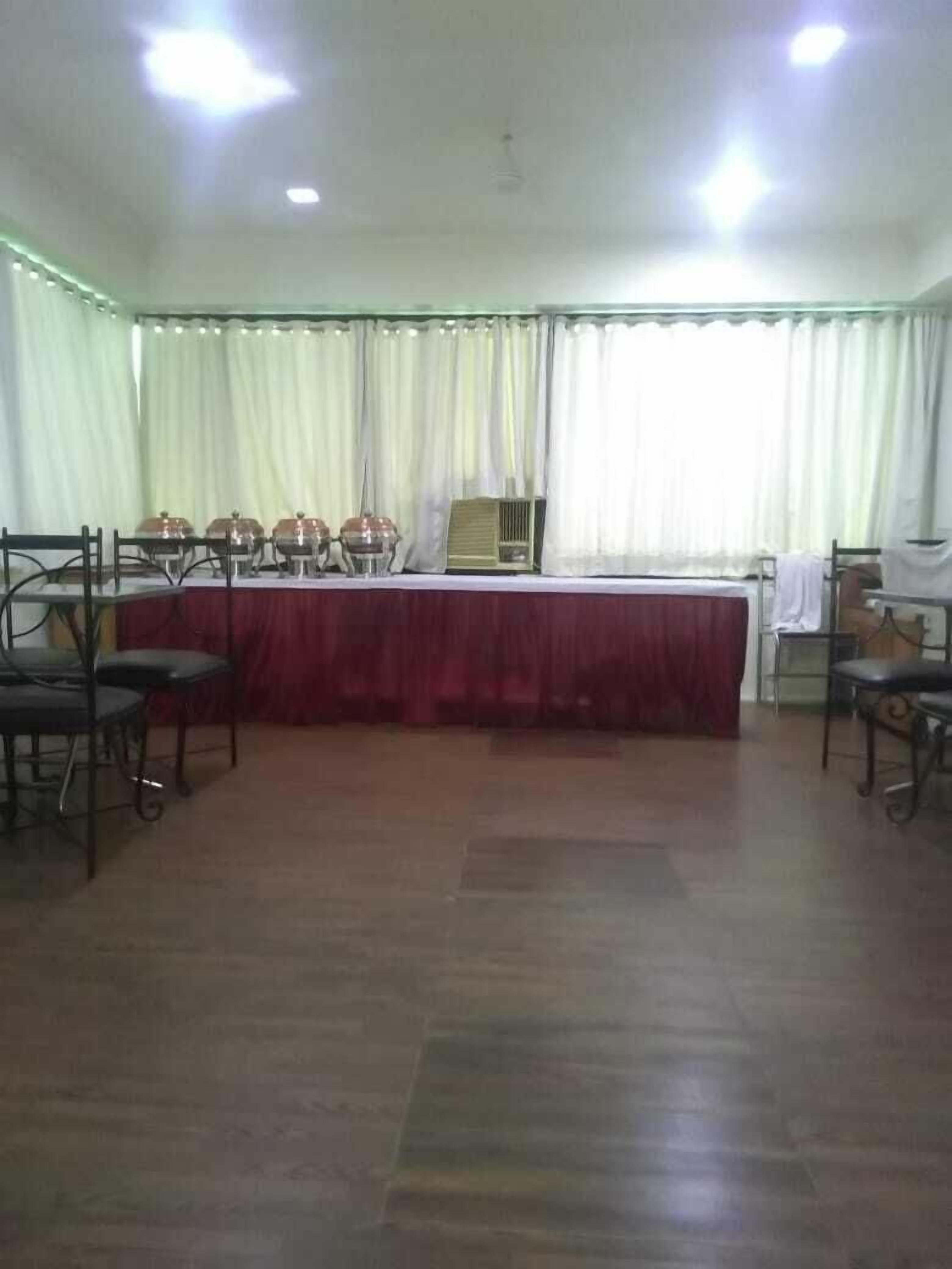 A conference room with a long table, chairs, and curtains.