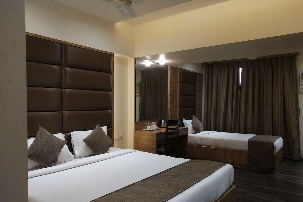Een hotelkamer met twee bedden, een bureau, een stoel en een grote spiegel.