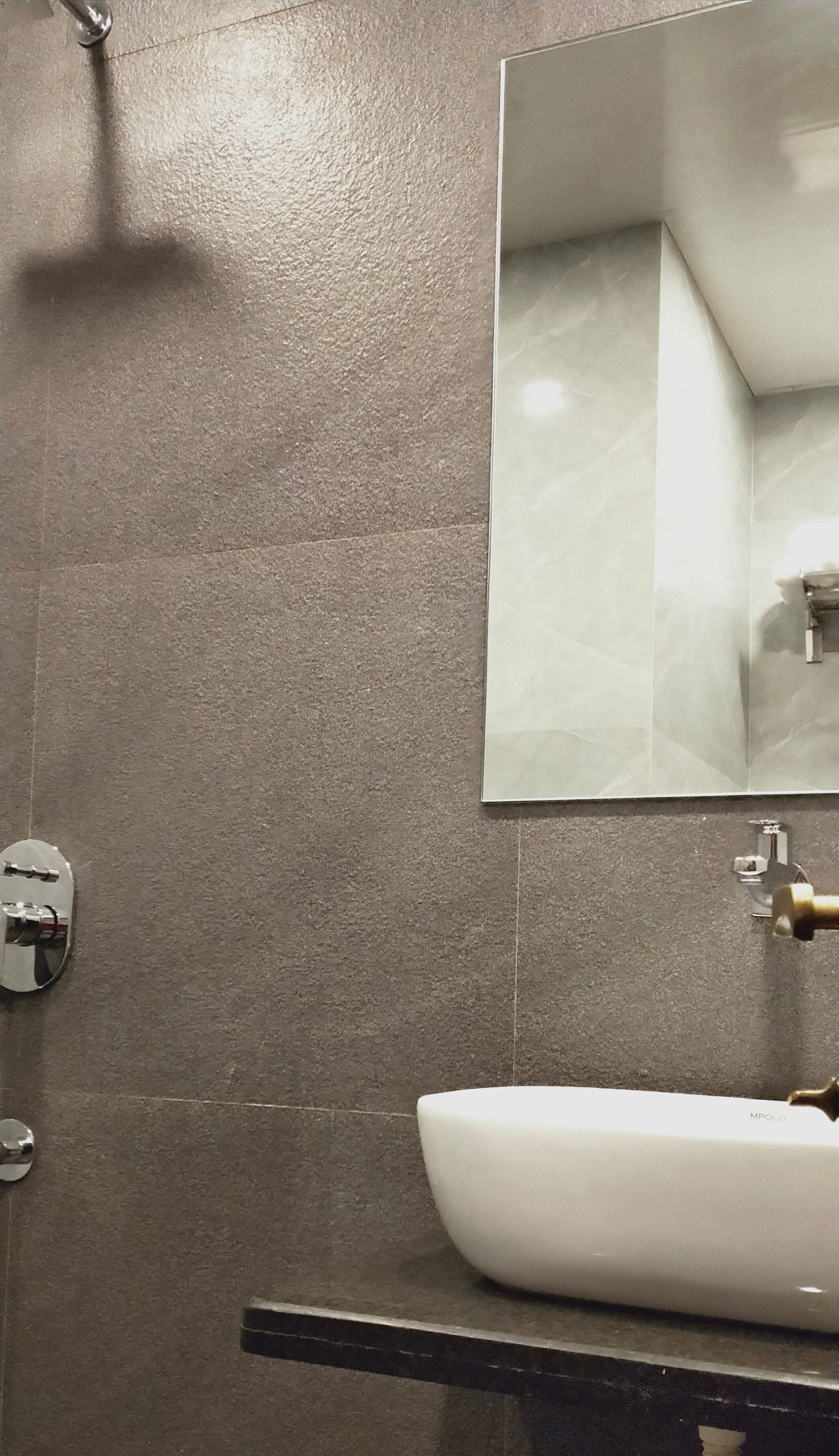Un baño con lavamanos blanco, espejo y ducha.