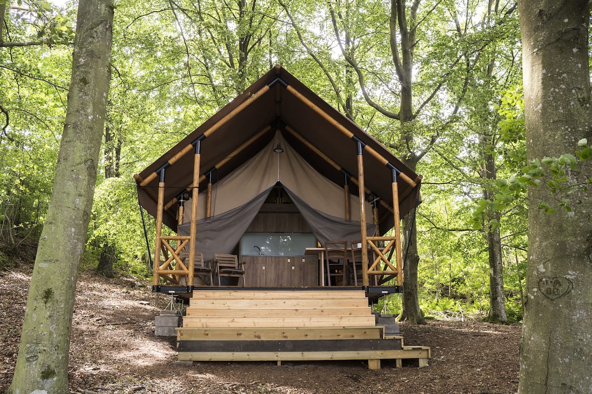 A wooden cabin with a pitched roof, built into a forested area.