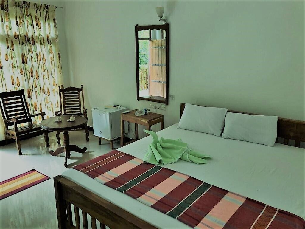 A hotel room with a bed, a desk, a chair, and a window with curtains.