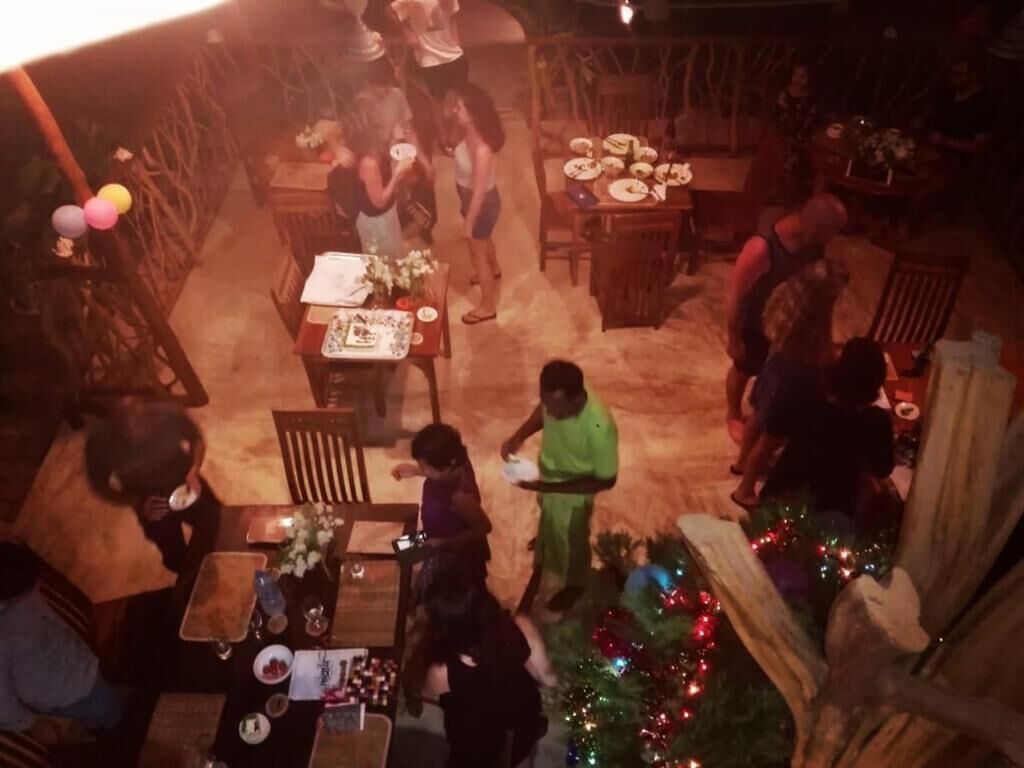 A dining area with tables and chairs, a Christmas tree, and a buffet setup.